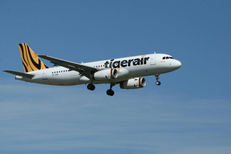 A Tigerair commercial airplane flying against a clear blue sky, showcasing aviation and travel.